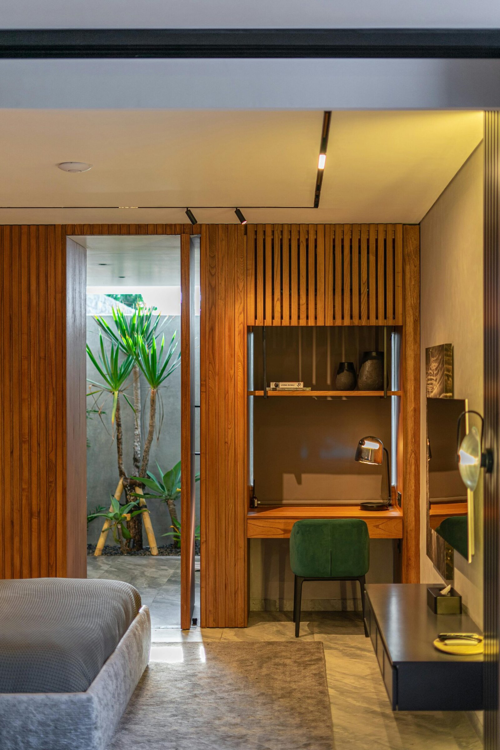 A stylish bedroom featuring modern wooden decor, desk, and indoor plant view.